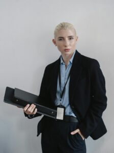 Confident businesswoman standing with folder against white wall