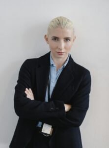 Positive woman in formal clothes standing with arms crossed